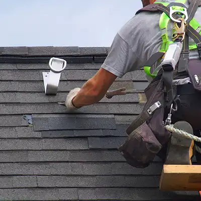 Close up of a roofer repairing a residential roof by replacing missing gray shingles